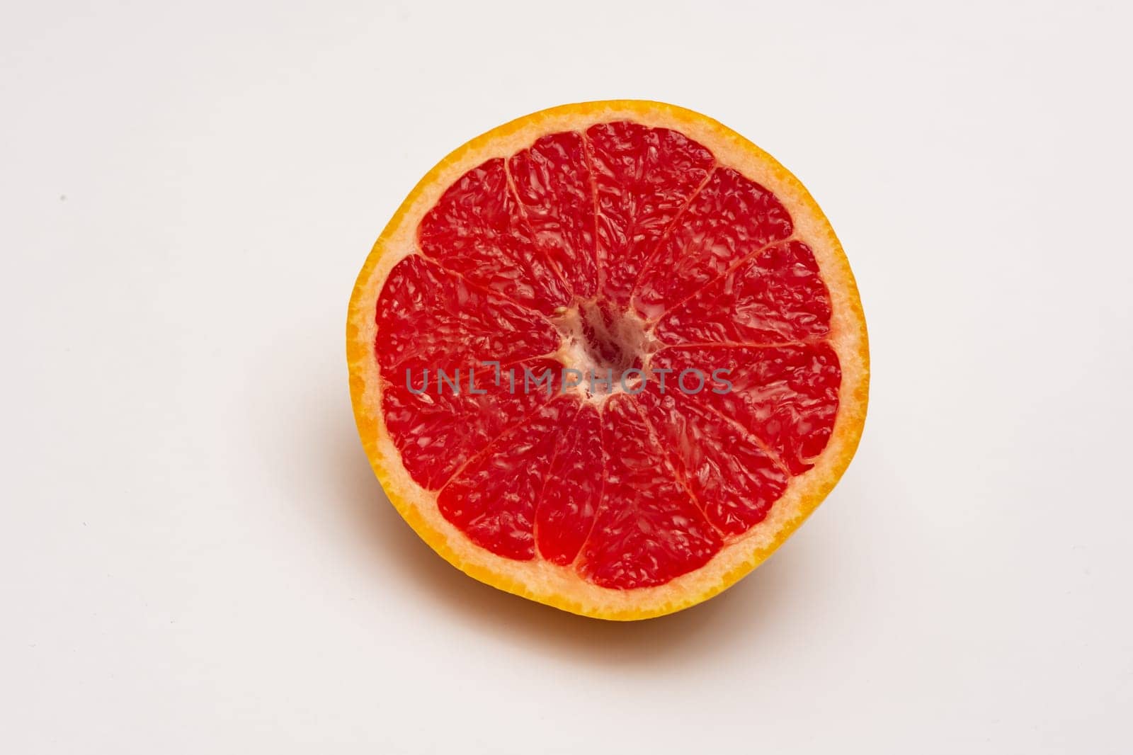 Sliced side of a grapefruit with red pulp isolated on a white background