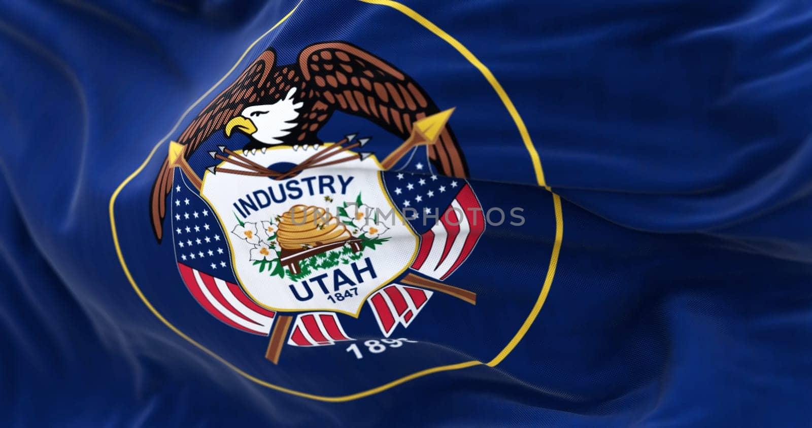 The Utah state flag fluttering in the wind. State seal surrounded by a golden circle on a dark blue background. 3D illustration render. Selective focus. Close-up. Rippled textile background