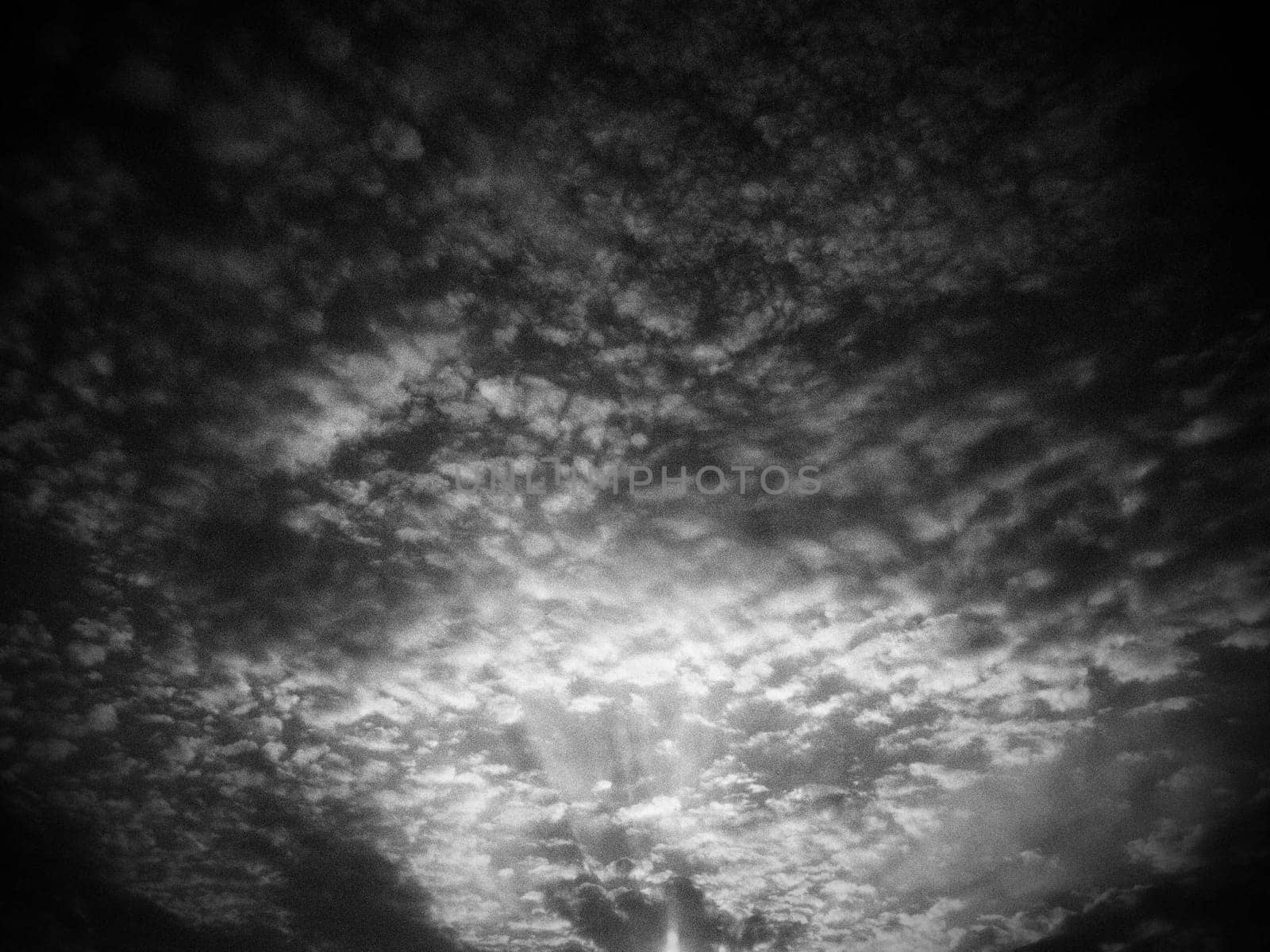 Sunset or sunrise. Clouds in the evening or morning sky. Sun rays. Beautiful landscape. Black and white monochrome photography in retro or vintage style. Increased level of photo noise as an art trick