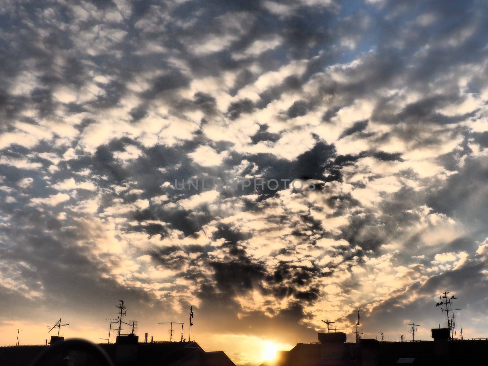 Black, gray and yellow sunset sky cloud. Dramatic sunset sky. Wonderful sunset. Clouds in the evening sky. The sun's rays pierce the clouds. Beautiful landscape. The sun goes down
