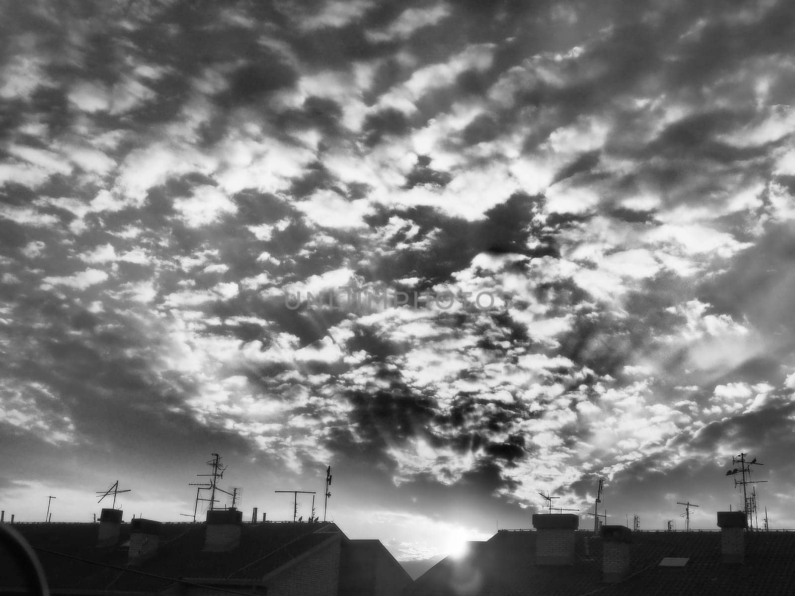 Sunset or sunrise. Clouds in the evening or morning sky. Sun rays. Beautiful landscape. Black and white monochrome photography in retro or vintage style. Increased level of photo noise as an art trick