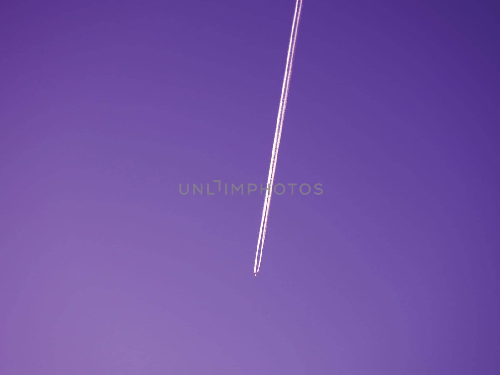 Airplane flying in the sky. Evening purple sky. Emissions of kerosene or heptyl rocket fuel. Environmental concept. Aviation business and passenger transportation.