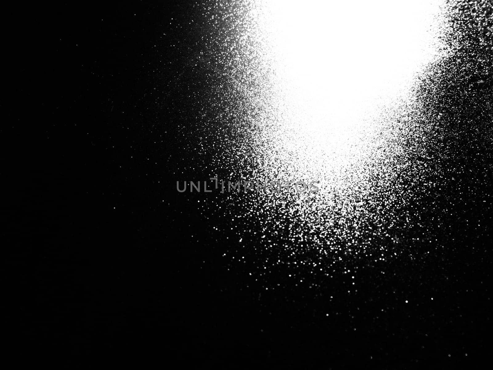 White bokeh and beam on a black background. Blurred glow from above on a dark surface. Night or space theme. Bokeh for the holiday. Abstract background. Glare, ray and light shine from above.