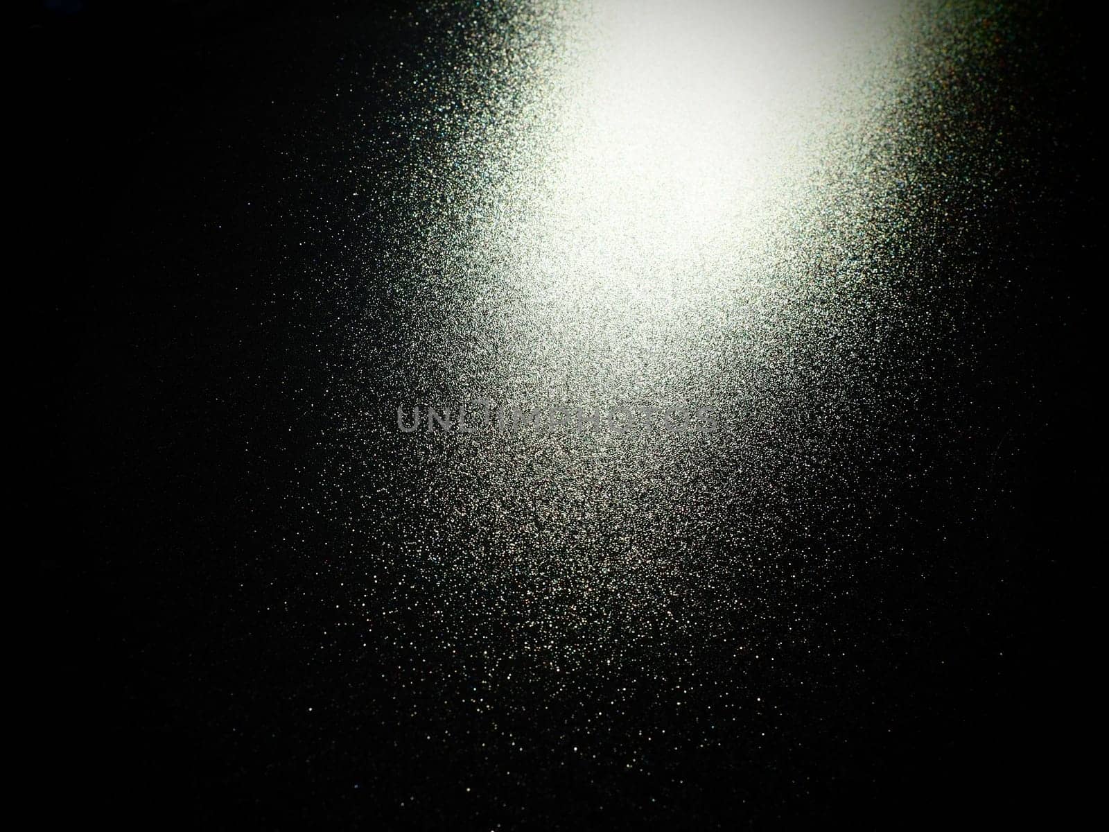 bokeh and beam on a black background. Blurred glow from above on a dark surface. Night or space theme. Bokeh for the holiday. Abstract background. Glare, ray and light shine from above