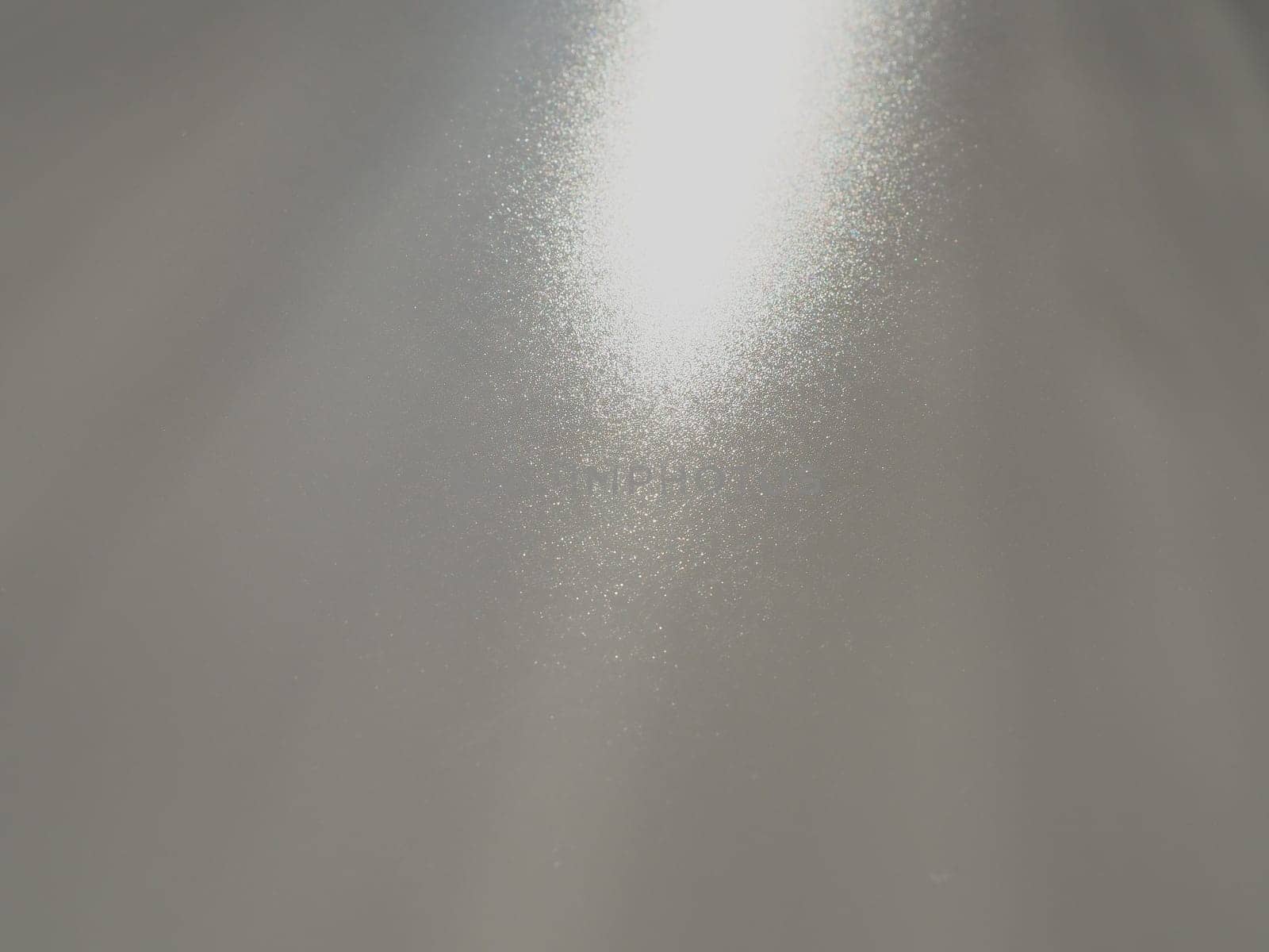 Diagonal rays of light on a gray background. Blurred abstract background light effect, light leaks. Side surface illumination. Small sparks and glow. Shine, glint or glare. Right top left down.
