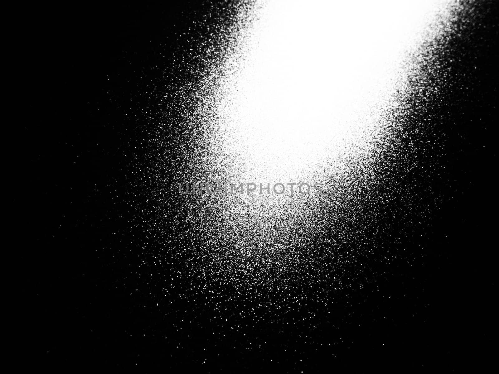 White bokeh and beam on a black background. Blurred glow from above on a dark surface. Night or space theme. Bokeh for the holiday. Abstract background. Glare, ray and light shine from above.