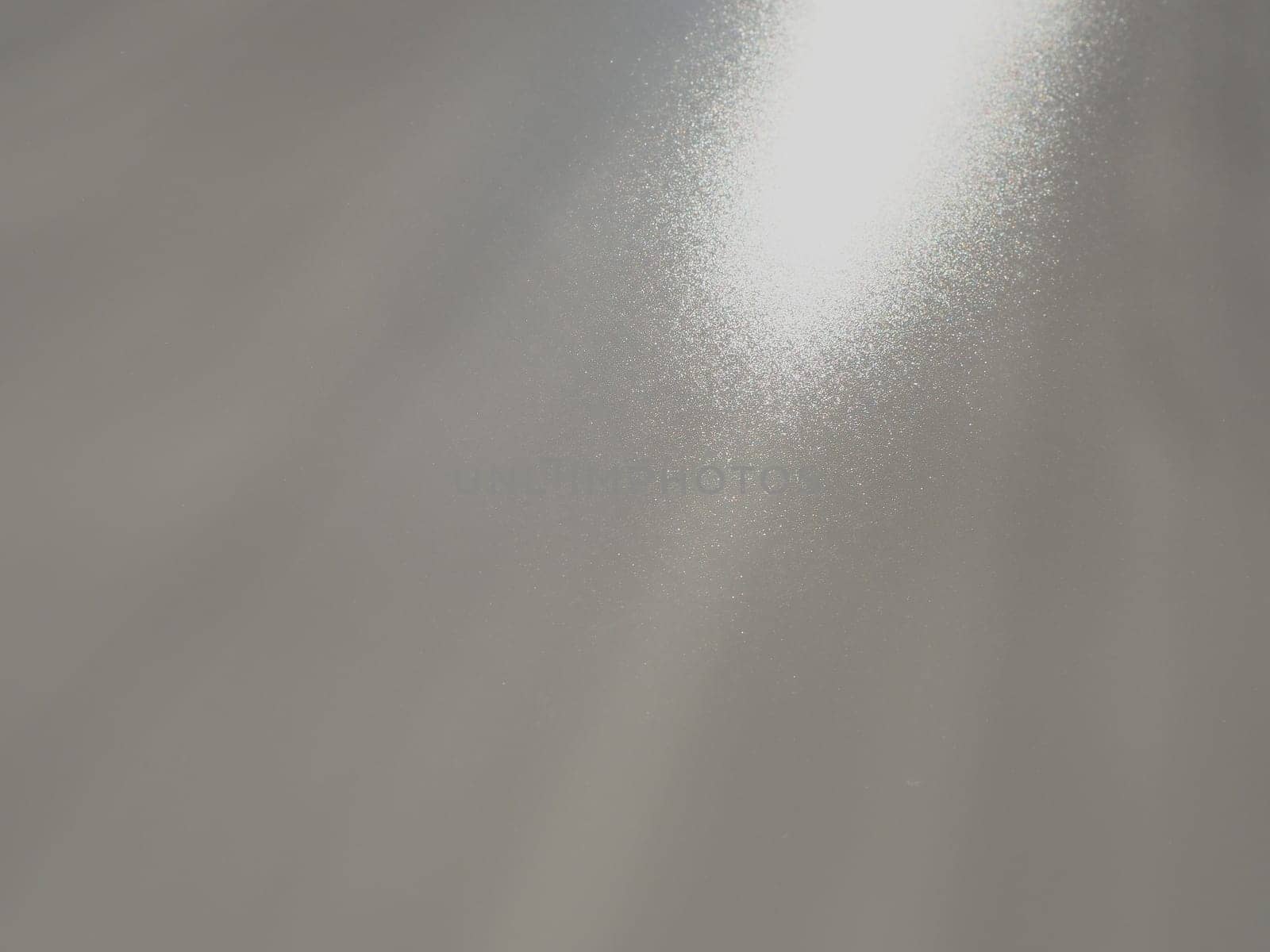 Diagonal rays of light on a gray background. Blurred abstract background light effect, light leaks. Side surface illumination. Small sparks and glow. Shine, glint or glare. Right top left down.