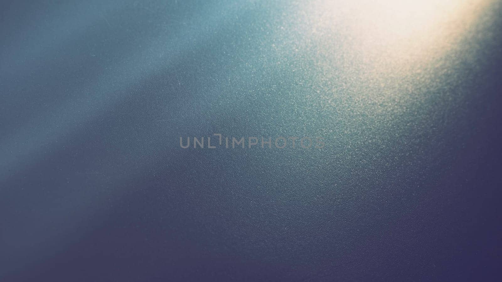 Oblique ray of light on a blue background. Blurred abstract backdrop with light effects and leaks. Side surface illumination. Divergent and asymmetric lines, stripes of light at angle. Yellowish glow
