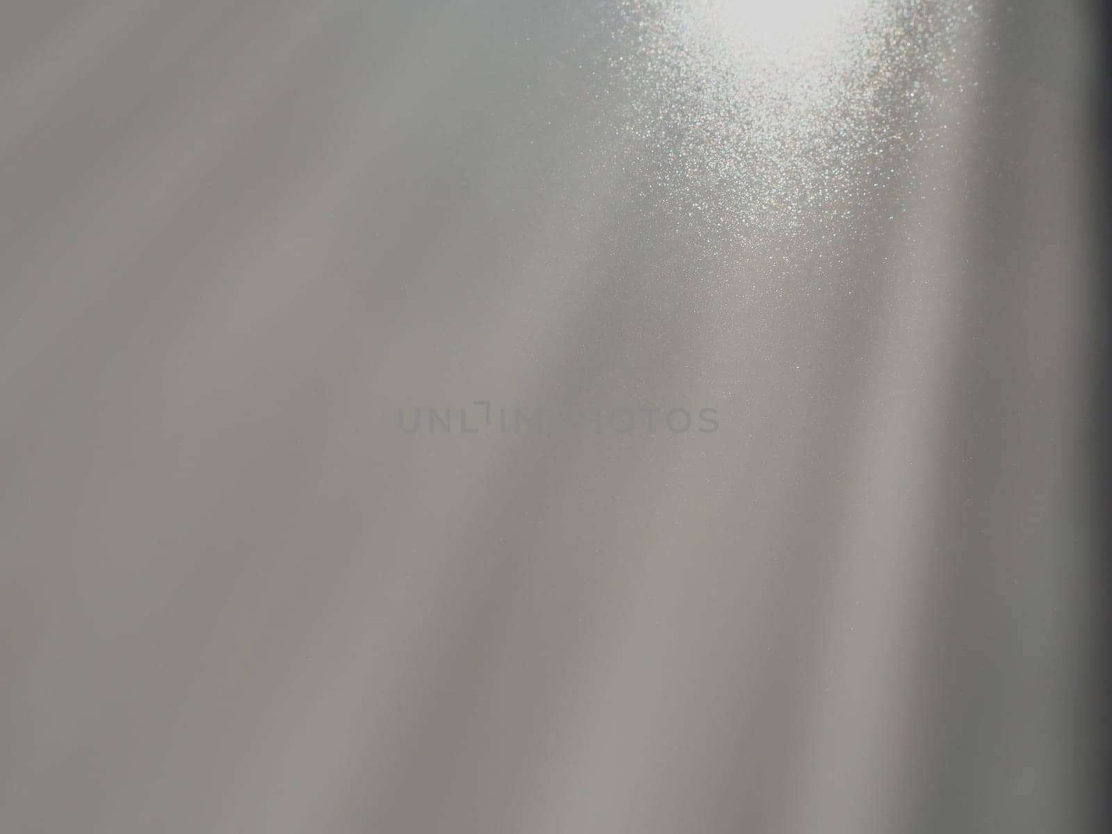 Diagonal rays of light on a gray background. Blurred abstract background light effect, light leaks. Side surface illumination. Small sparks and glow. Shine, glint or glare. Right top left down.