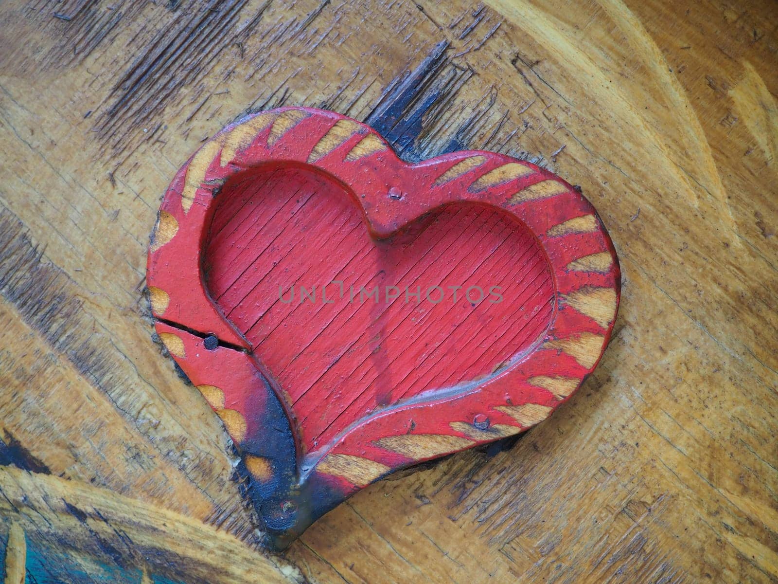 Carpentry heart shape on a wooden surface and painted red. A symbol of love and fidelity. Postcard for congratulations or recognition on Valentines Day. Signs of the influence of ignition or moisture