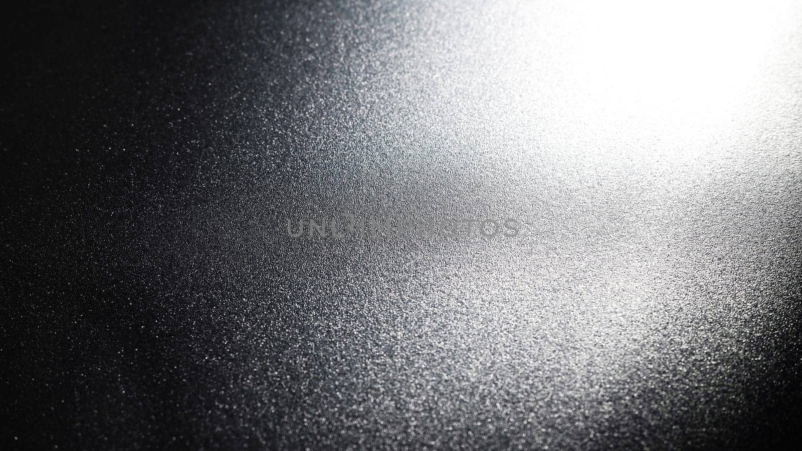 White bokeh and beam on a black background. Blurred glow from above on a dark surface. Night or space theme. Bokeh for the holiday. Abstract background. Glare, ray and light shine from above.