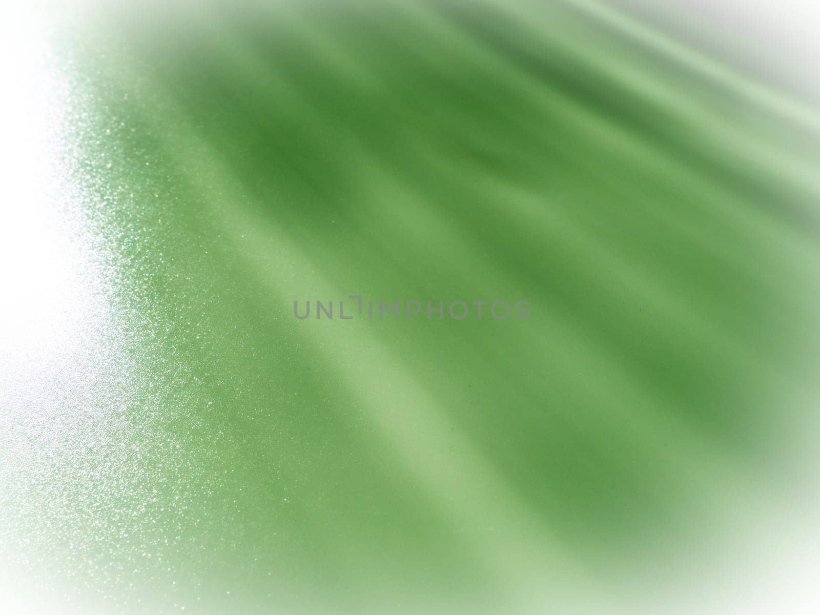 Diagonal rays of light on green background. Blurred abstract background light effect and leaks. Side illumination. Parallel and asymmetric lines, stripes of light at angle. Top-left to bottom-right