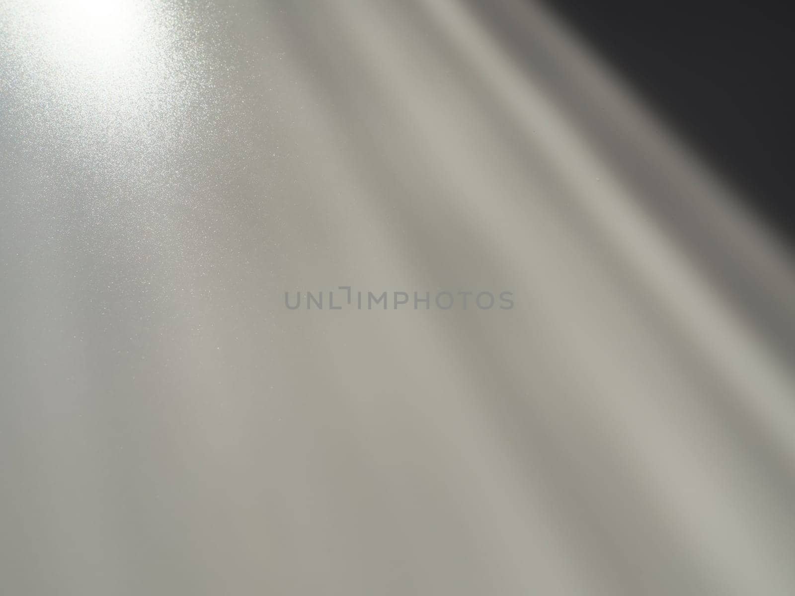 Diagonal rays of light on a gray background. Blurred abstract background light effect and leaks. Side surface illumination. Parallel, divergent and asymmetric lines, stripes of light at an angle.