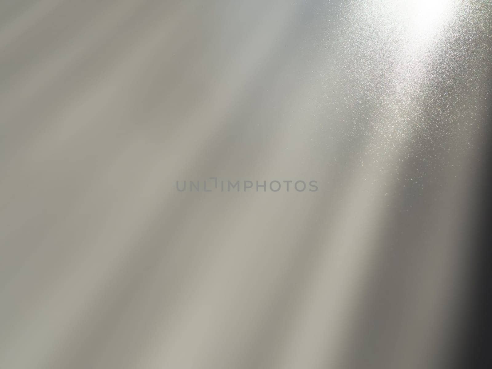 Diagonal rays of light on a gray background. Blurred abstract background light effect and leaks. Side surface illumination. Parallel, divergent and asymmetric lines, stripes of light at an angle