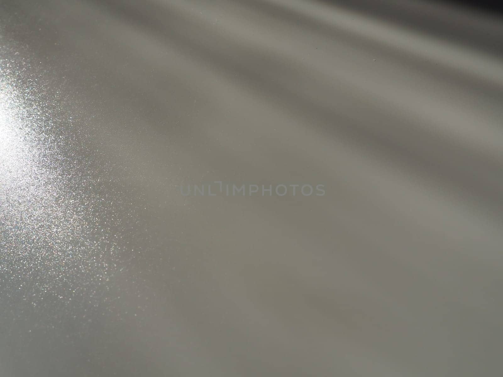 Diagonal rays of light on a gray background. Blurred abstract background light effect, light leaks. Side surface illumination. Small sparks and glow. Shine, glint or glare. Left top right down