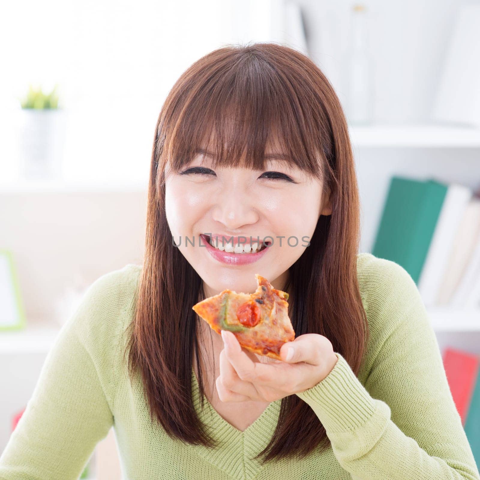 Asian female eating pizza at home. Woman living lifestyle indoors.