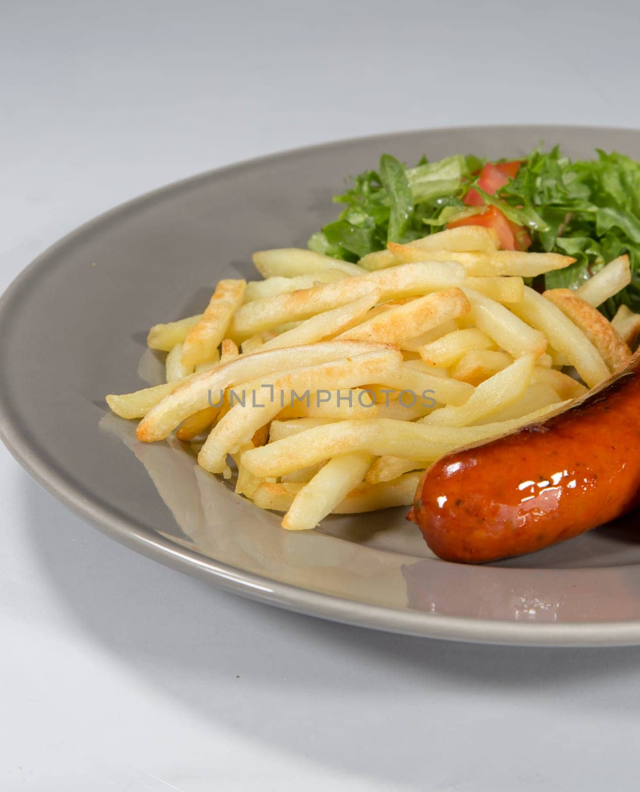 Sausage and French Fries on a plate with white background.