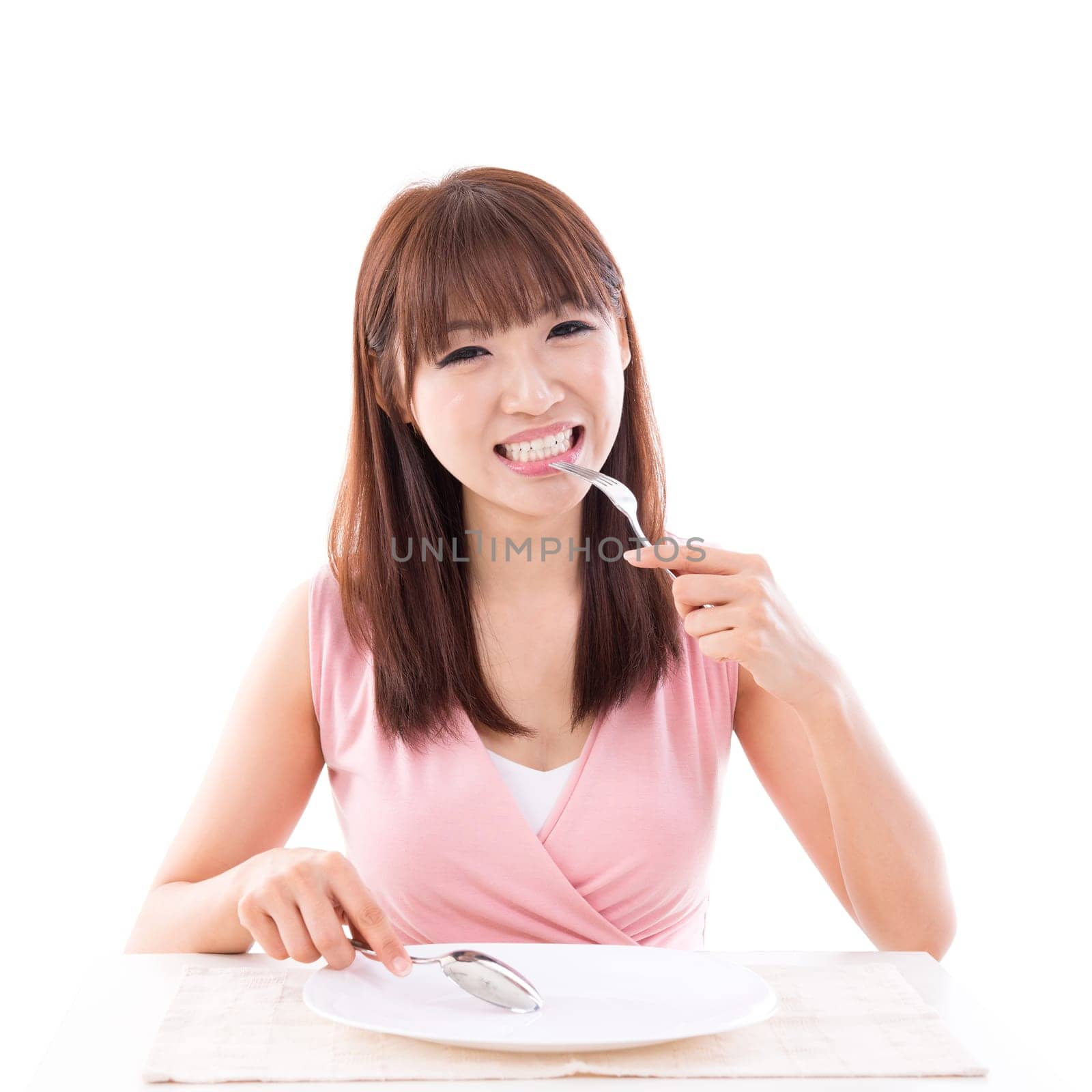 Asian girl eating food with fork and spoon, empty plate ready for food. Young woman living lifestyle.