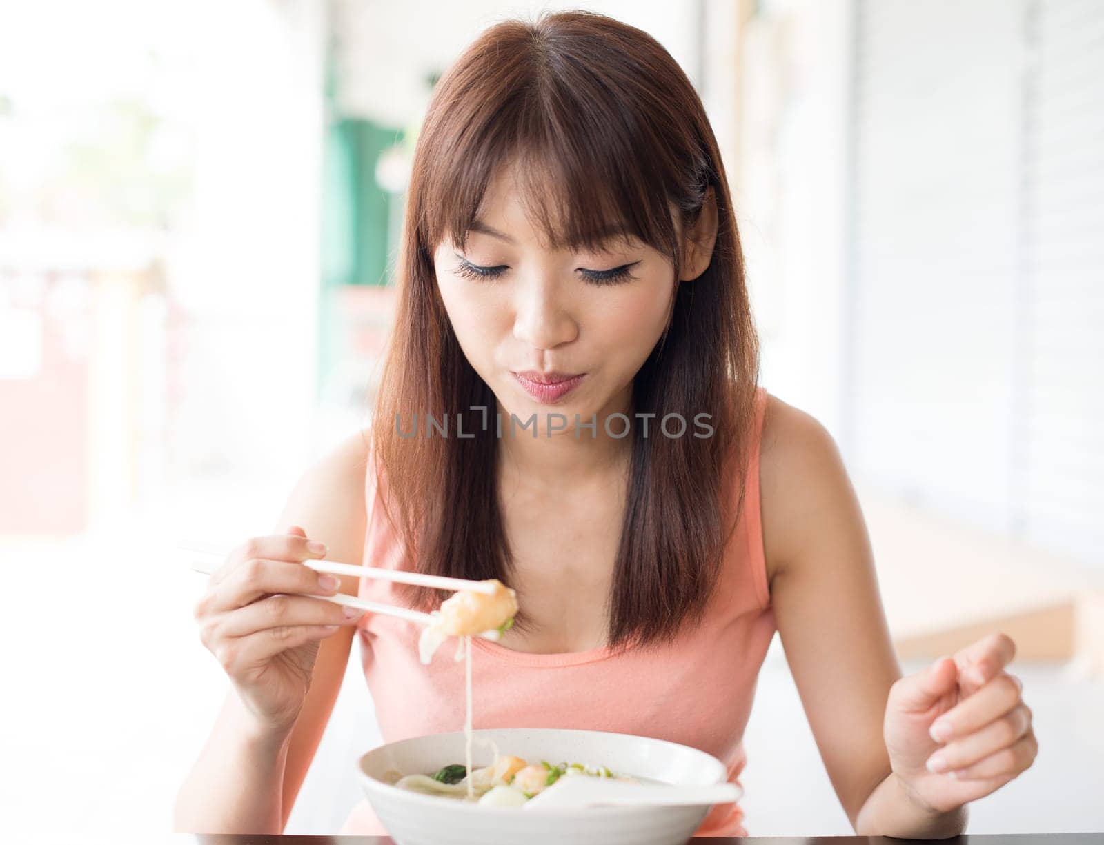 Asian girl eating dumpling noodles at Chinese restaurant. Young woman living lifestyle.