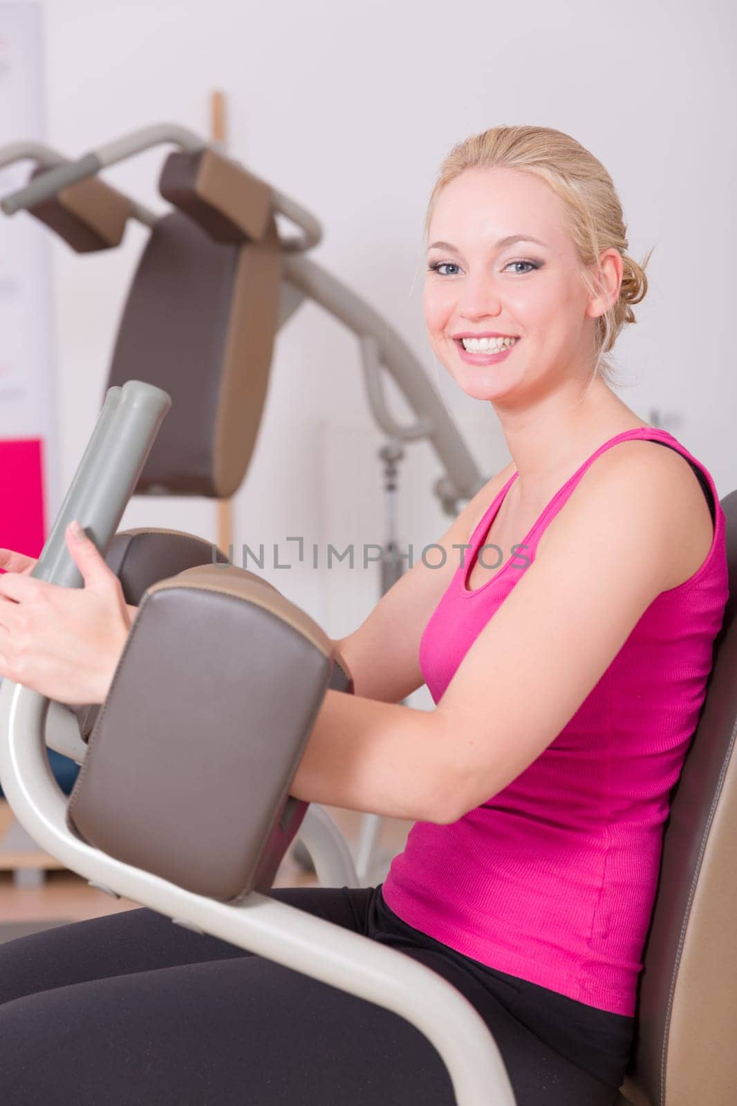 A young pretty woman in a pink shirt doing exercises in a gym