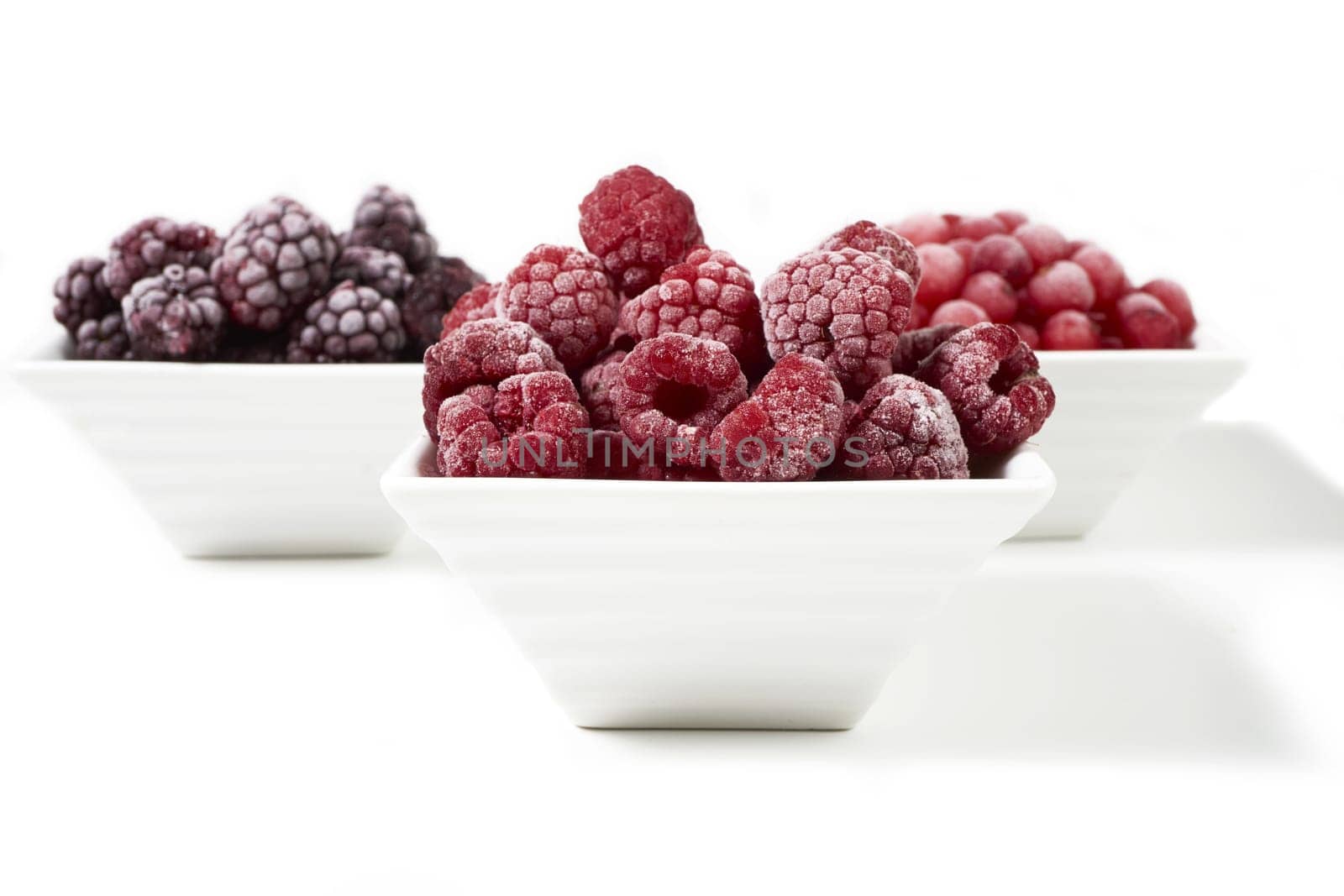 Three bowls of different frozen berries
