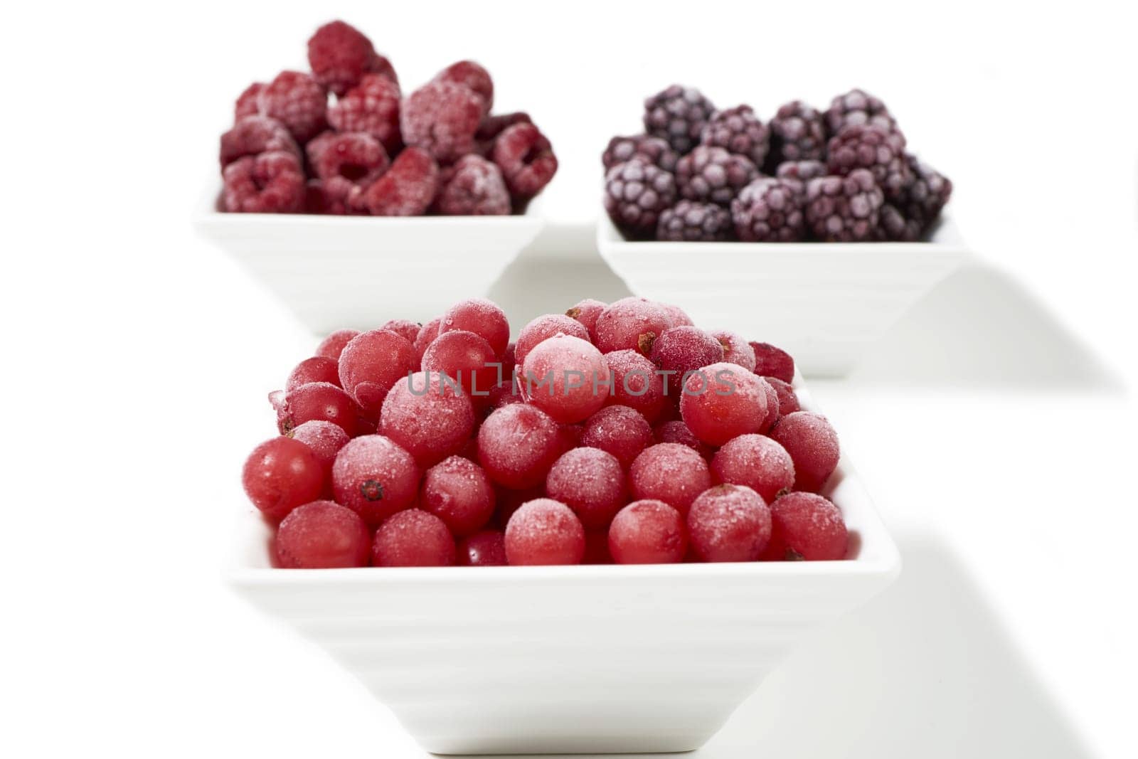 Three bowls of different frozen berries