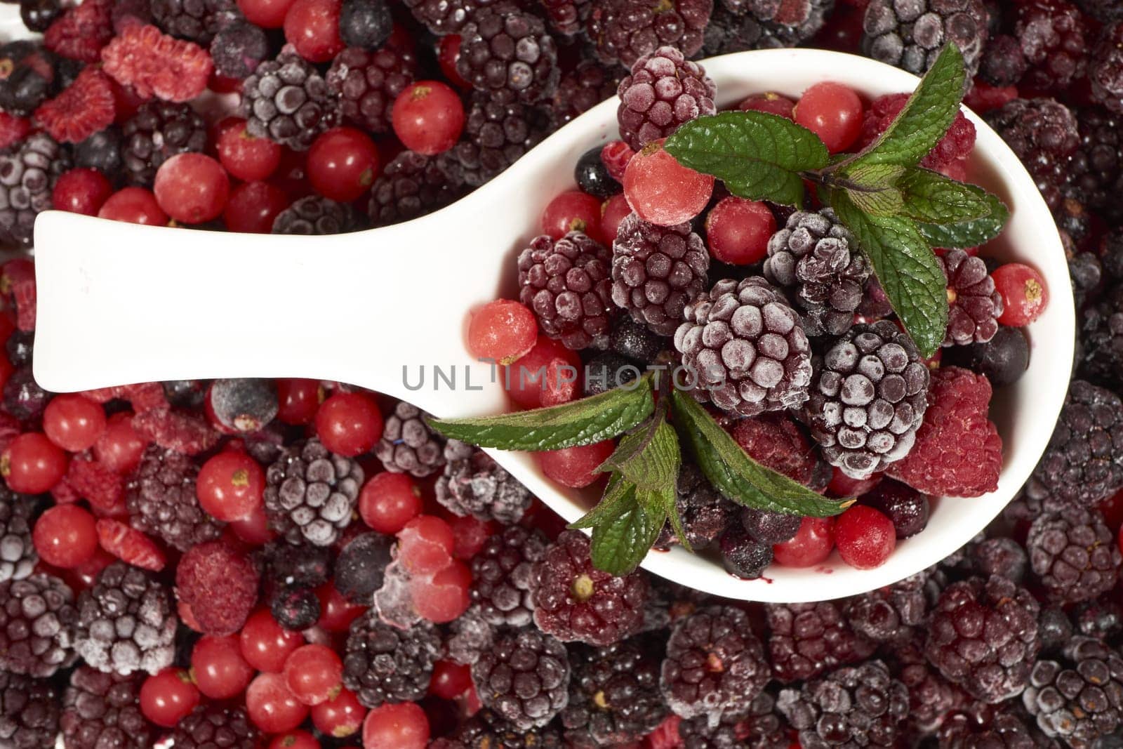 Frozen berries with mint in porcelain bowl