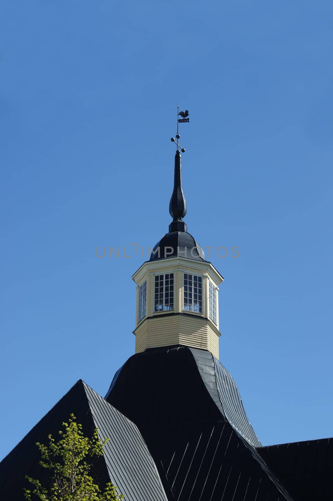 weather vane rooster on the spire of an old house, high in the blue sky