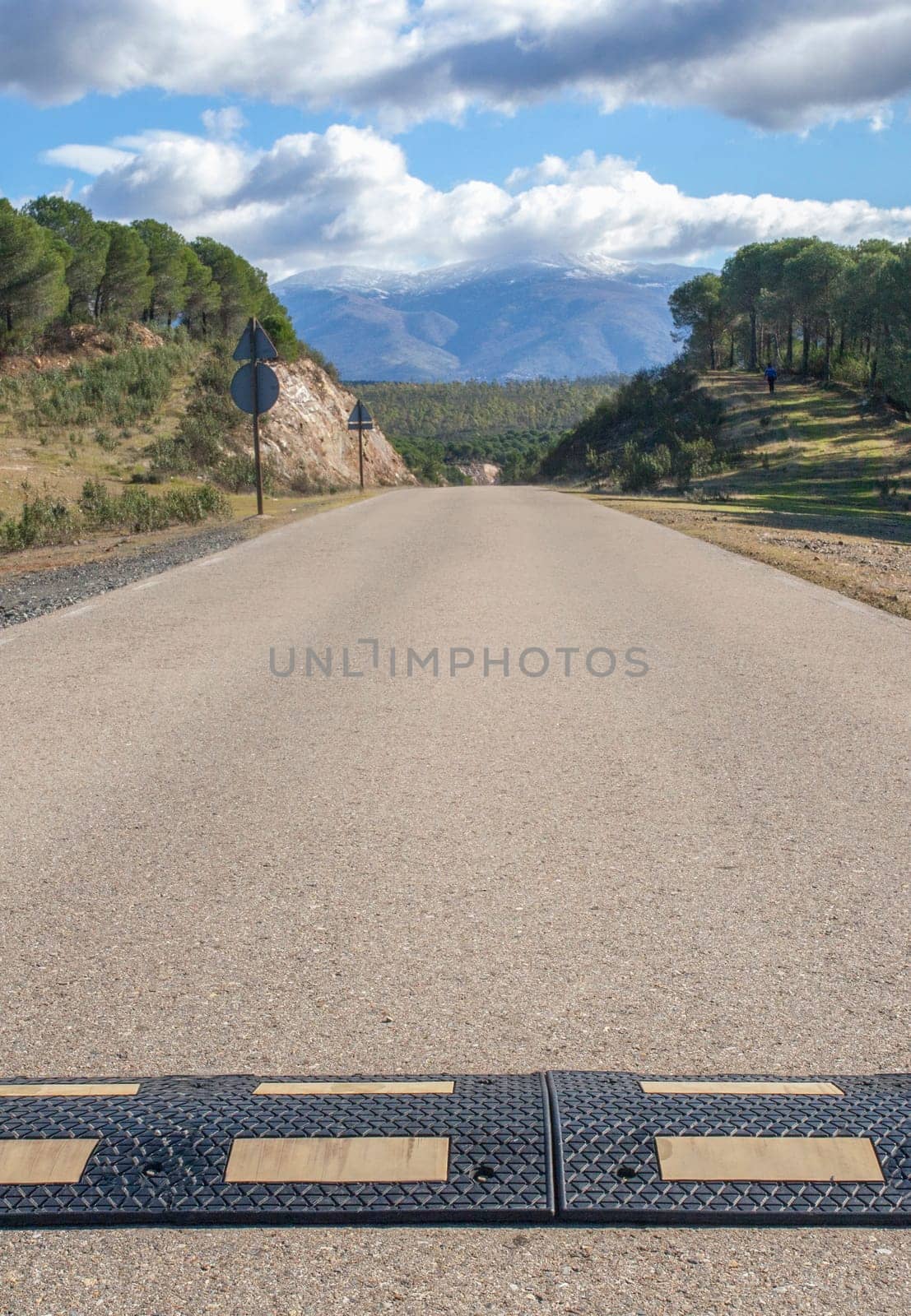 Speed bumps installed a local country road. Snowy mountains background