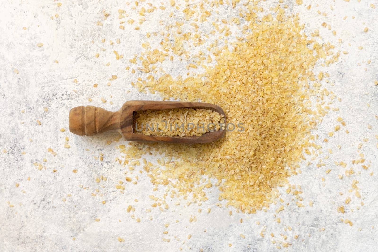 Wooden scoop of Dry uncooked bulgur wheat grain top view, copy space. Vegetarian and Vegan, Mediterranean and Middle Eastern cuisine. Healthy lifestyle