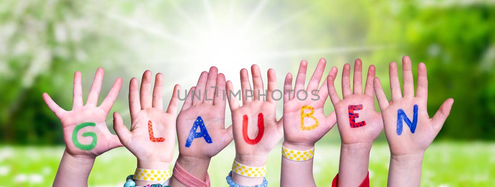 Children Hands Building Colorful German Word Glauben Means Believe. Sunny Green Grass Meadow As Background.