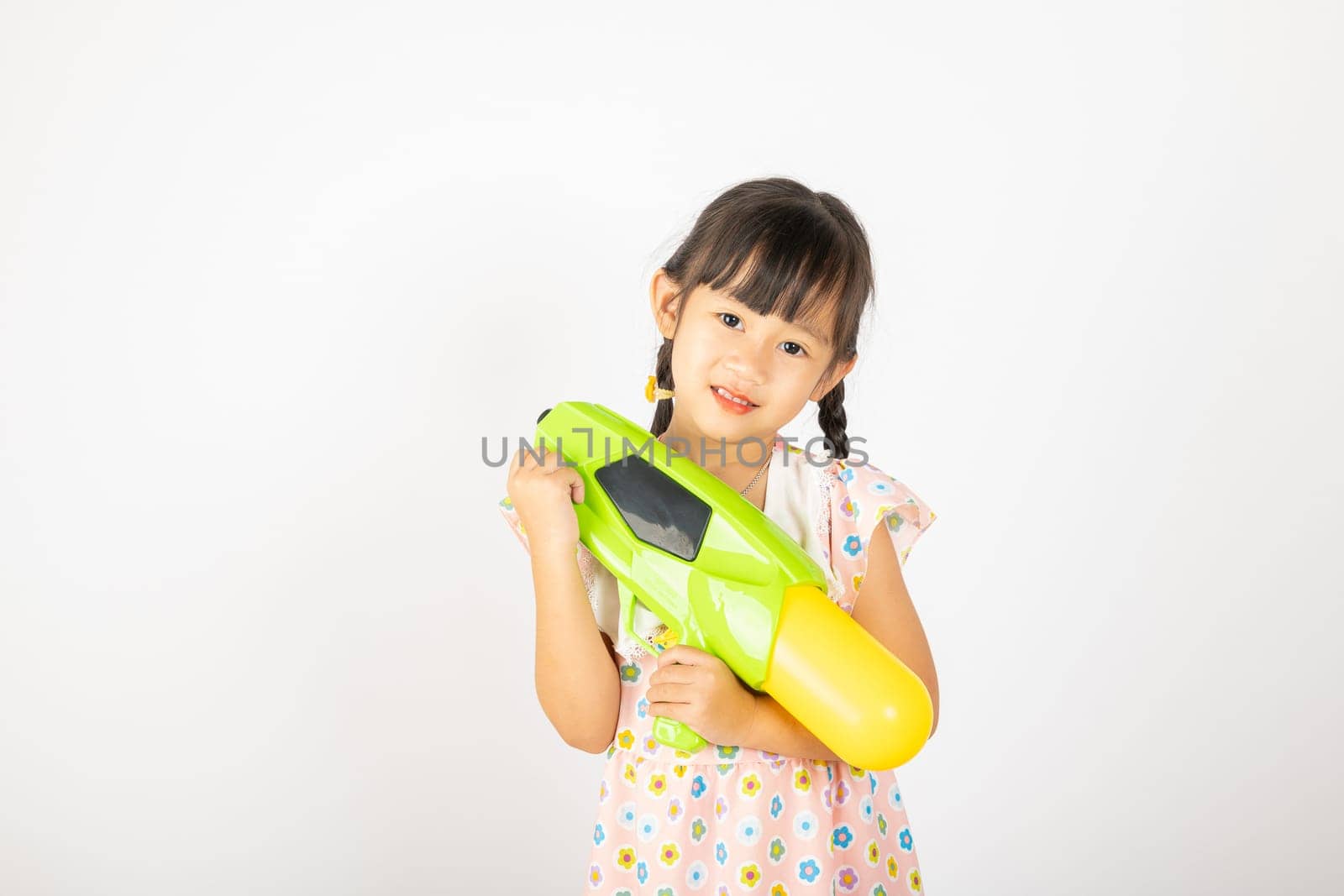 Happy Songkran Day, Asian little girl holding plastic water gun, Thai child funny hold toy water pistol and smile, isolated on white background, Thailand Songkran festival national culture concept