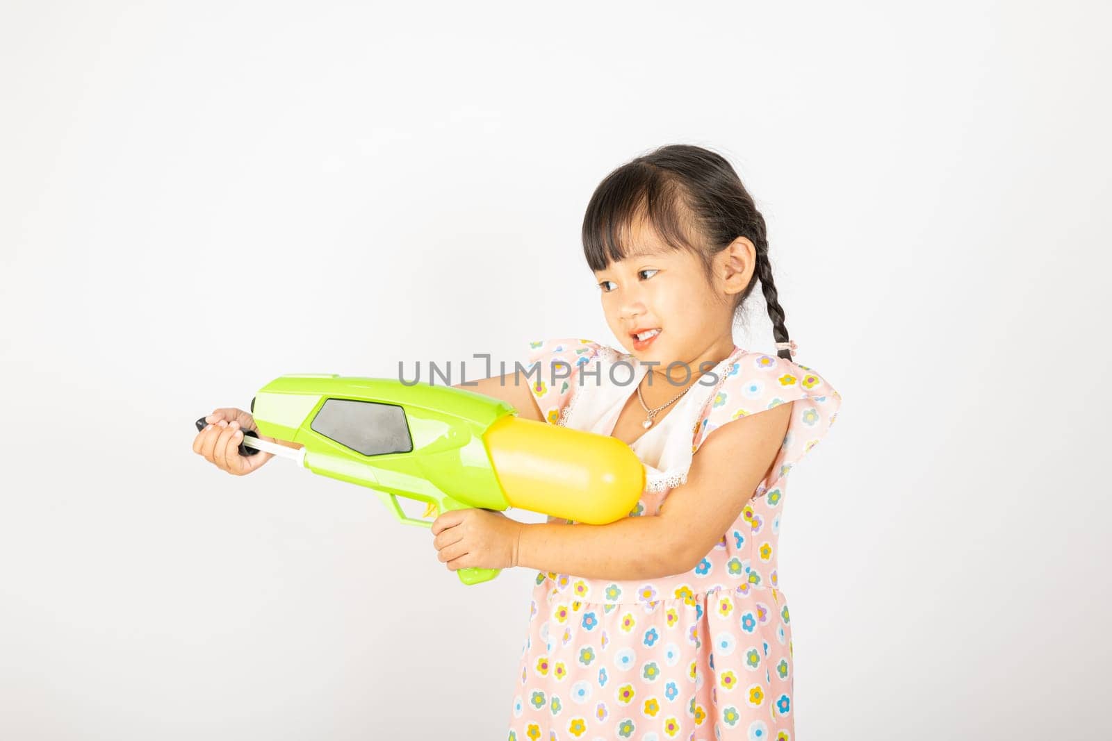 Happy Songkran Day, Asian little girl holding plastic water gun, Thai child funny hold toy water pistol and smile, isolated on white background, Thailand Songkran festival national culture concept