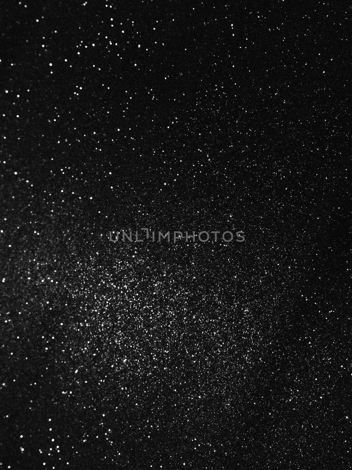 Black bokeh texture on black background. White glitter or illuminated dust.