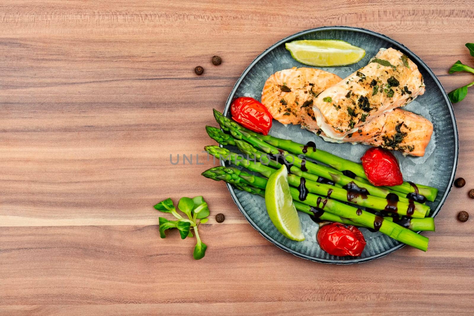Healthy lunch of trout, asparagus and tomato on a wooden table.