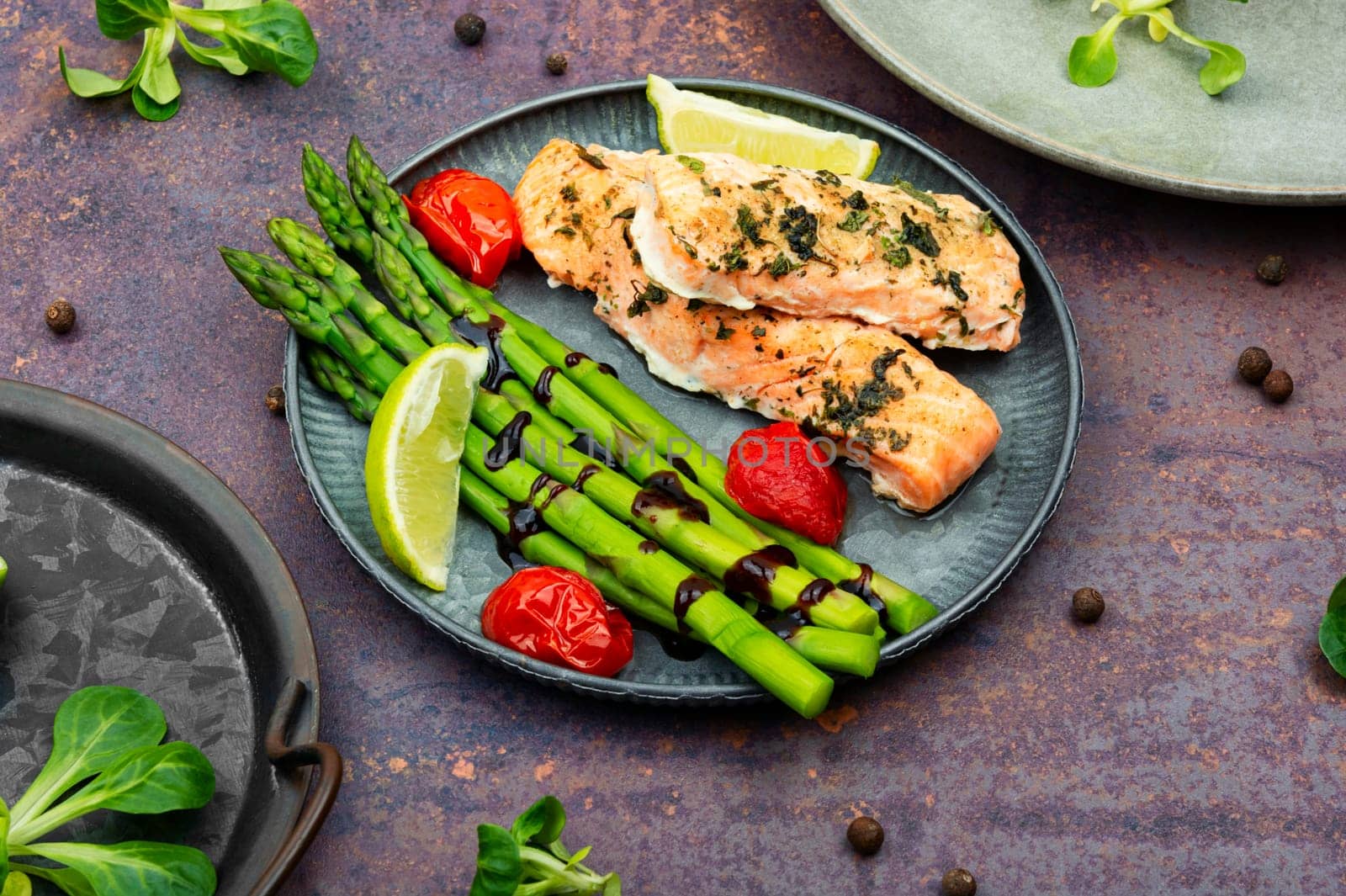 Healthy lunch of trout, asparagus and tomato on a wooden table.