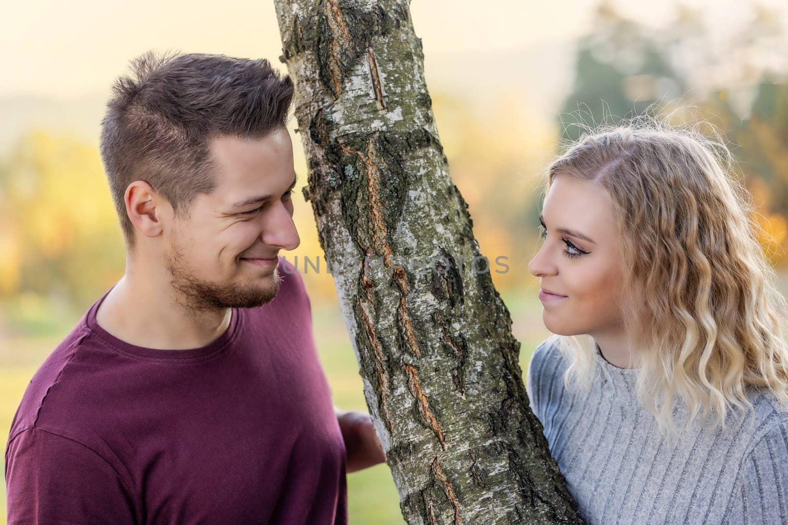 Young loving couple is posing in the autumn park. Horizontally.