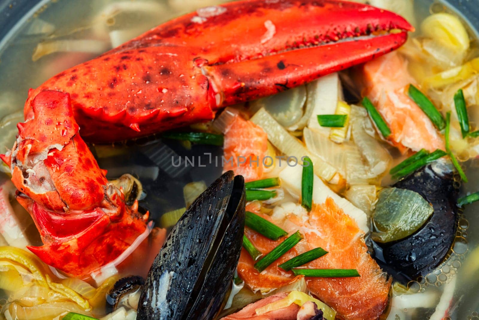 Seafood soup with lobster, mussels, shrimps and fish. Soup in ceramic bowl. Tom yum. Copy space