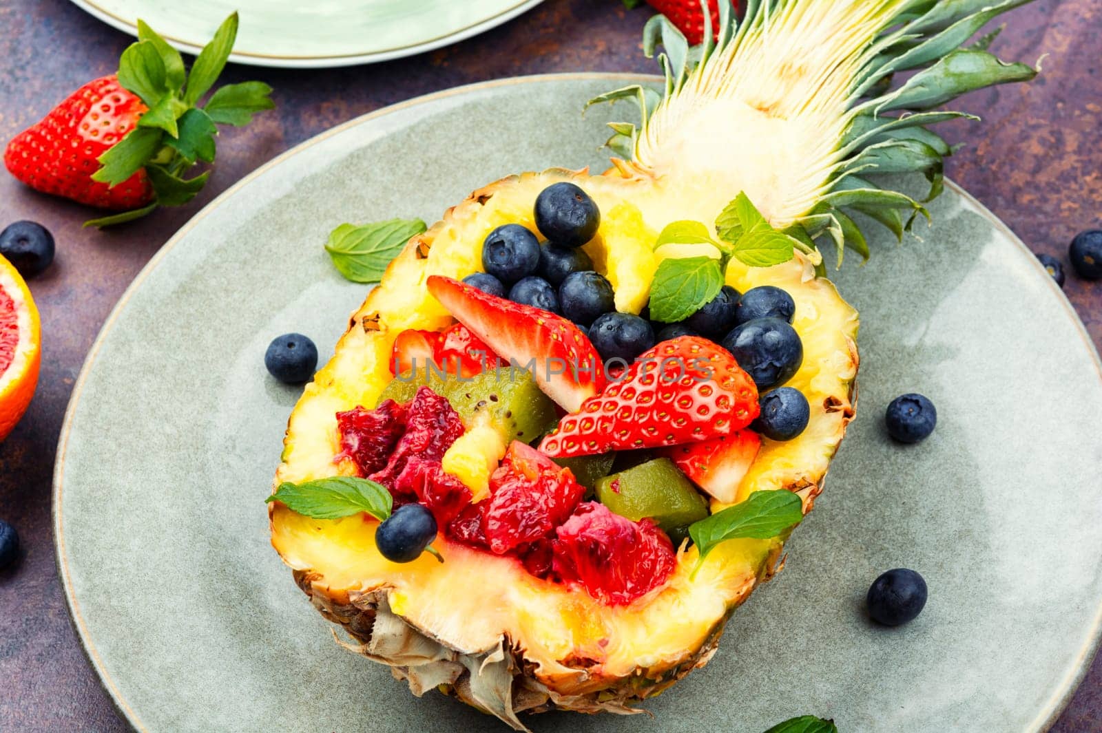 Fruit salad of strawberries, kiwi, berries and orange served in half a pineapple. Healthy eating