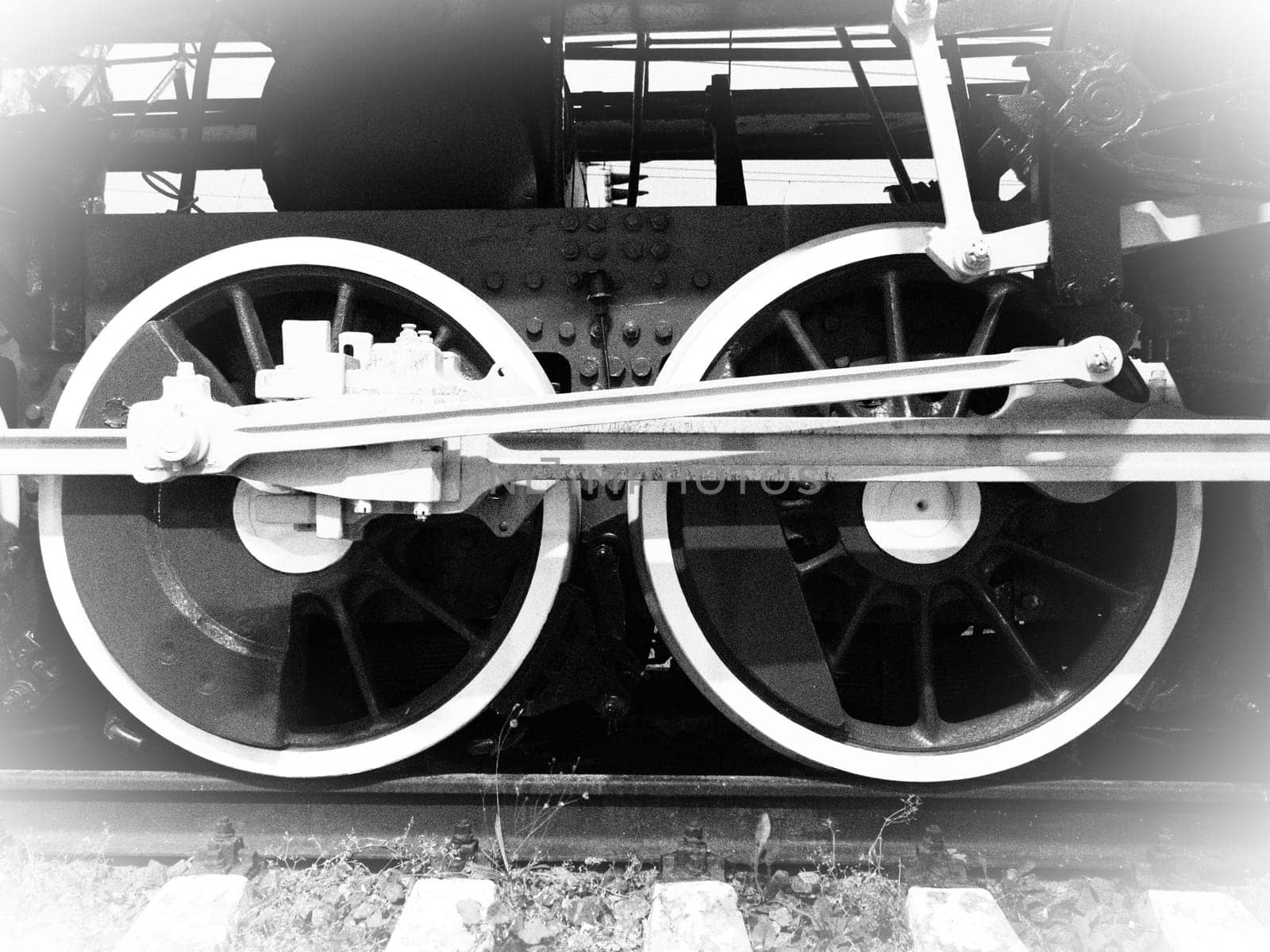 Retro train wheels. Beautiful card. Sleepers and rails, pistons and guides. Locomotive of the 19th early 20th century with a steam engine. Vintage style. Black-white. White vignetting around the edges.