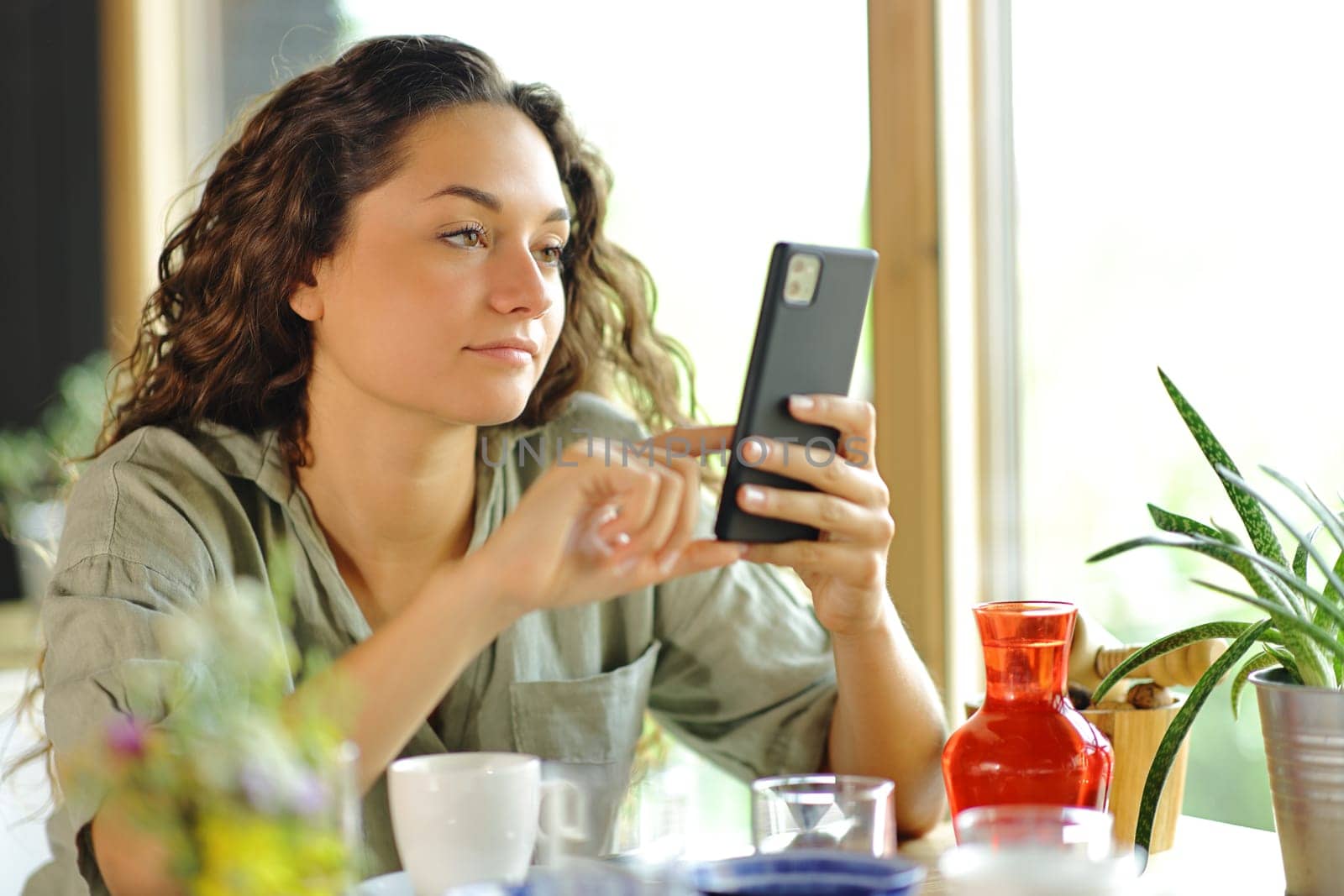 Serious woman checking smart phone sitting in a restaurant
