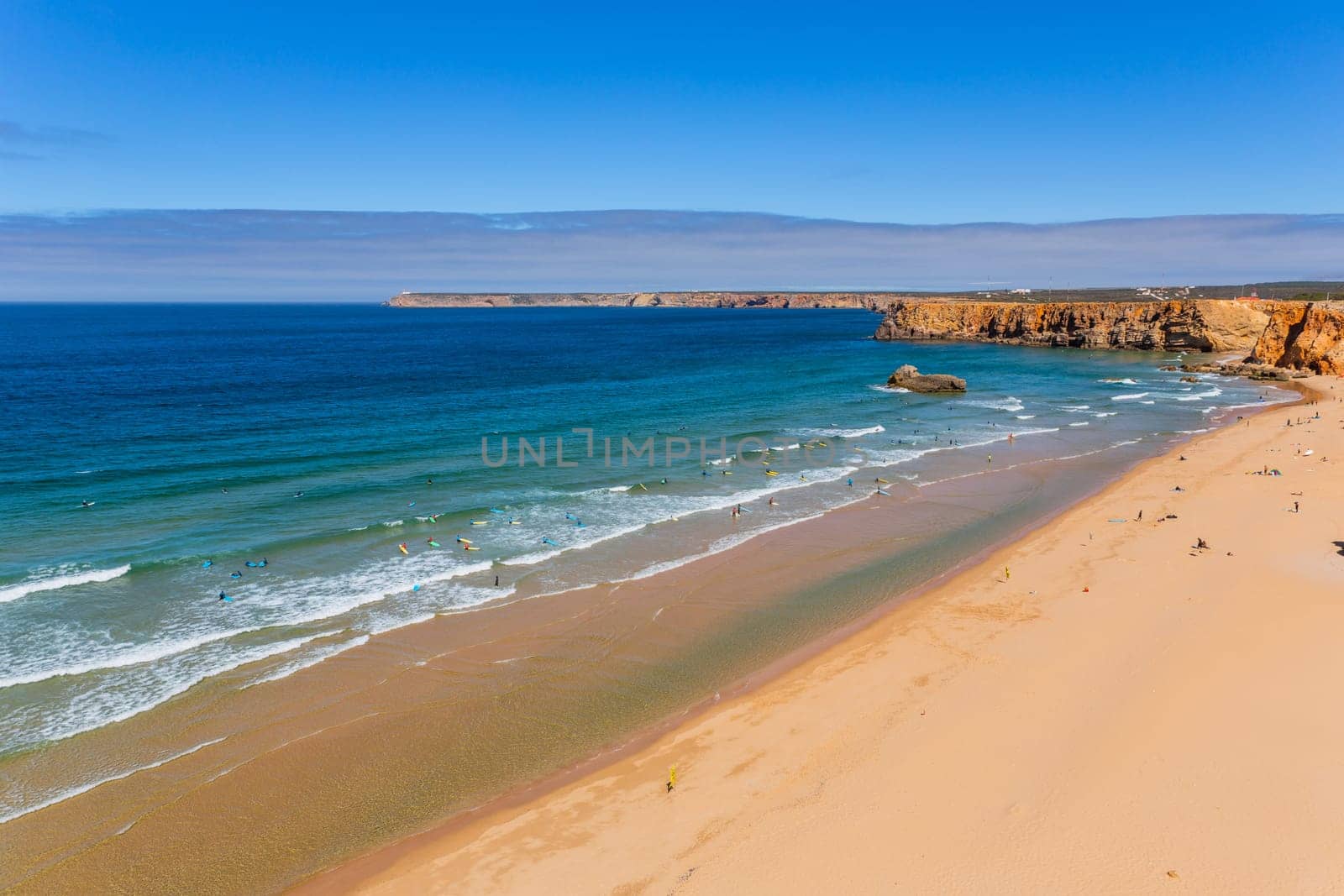 Sagres, Portugal - August 25, 2022: View of surfers on sandy beach near Sagres village in Algarve, Portugal