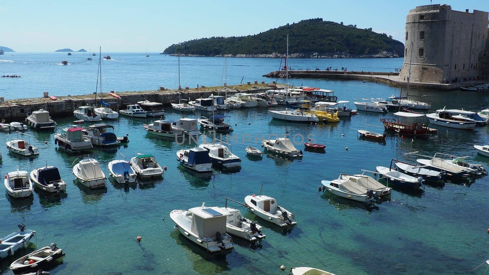 Dubrovnik, Croatia, 08.14. 2022 City port summer tourist attraction. Tourists walk, get into boats and ships and go on boat trips. Adriatic Sea. Travel and recreation. Private boats of local citizens