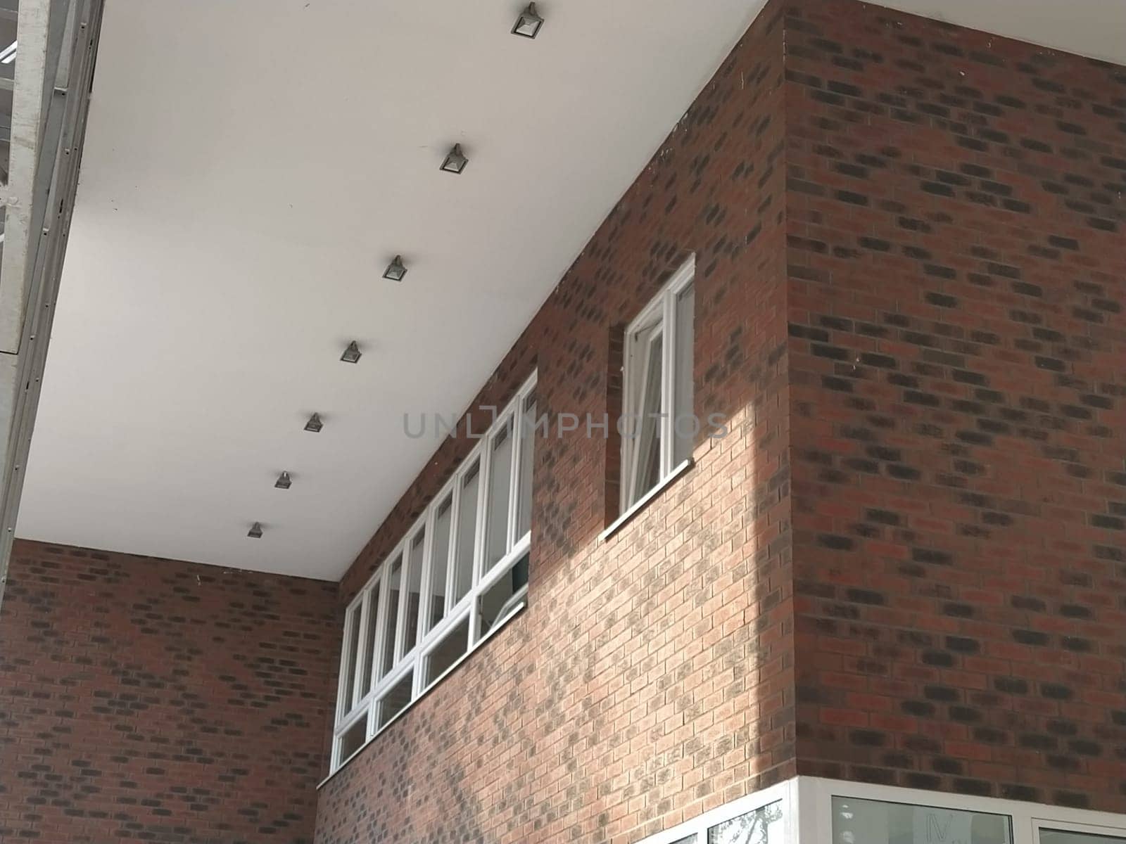 Exterior of the new school. New plastic white windows. Fashionable brown - red facing brick. Metal arch with canopy. Ceiling lighting. School entrance. Serbia, Sremska Mitrovica