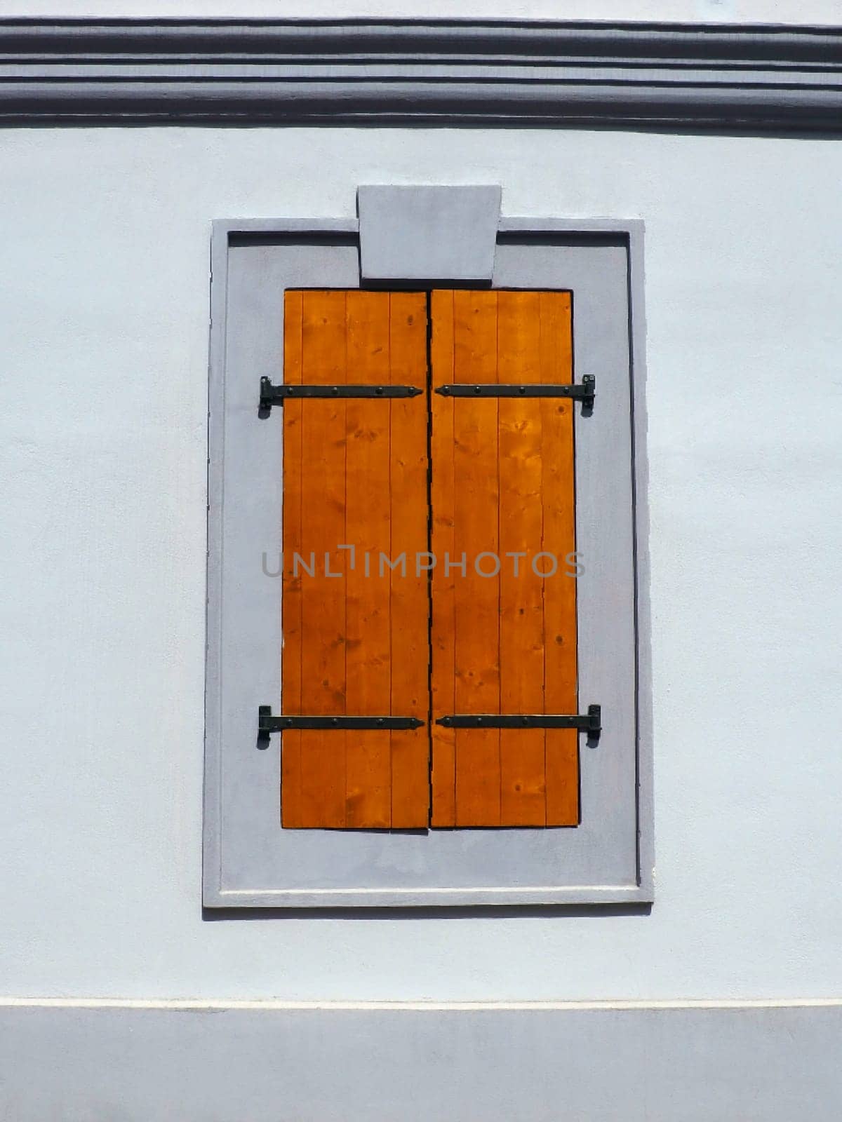 Window with old wooden shutters. Metal curly braces. White wall. Country style. Petrovaradin, Novi Sad, Serbia. Vintage retro architecture building facade