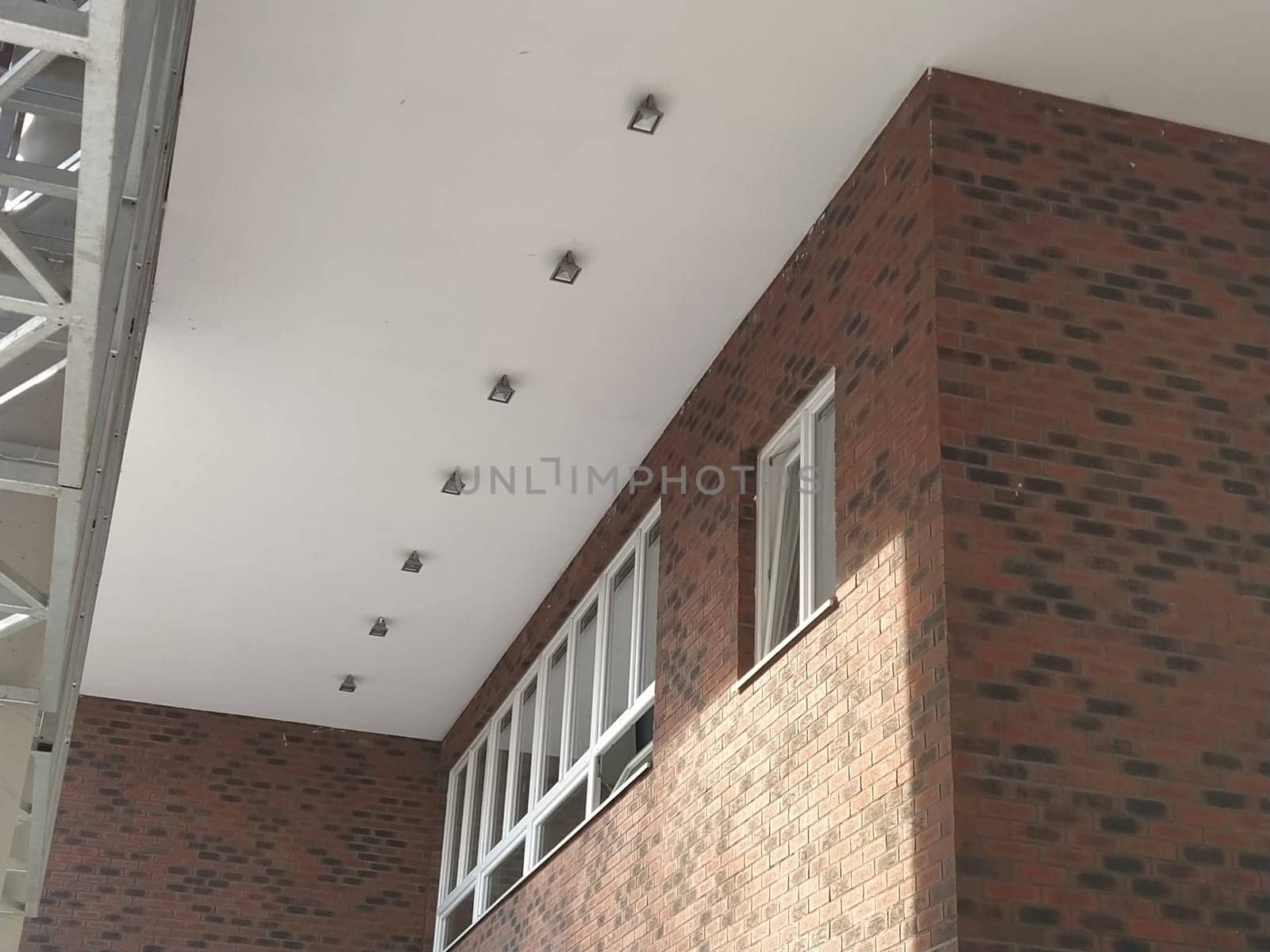 Exterior of the new school. New plastic white windows. Fashionable brown - red facing brick. Metal arch with canopy. Ceiling lighting. School entrance. Serbia, Sremska Mitrovica