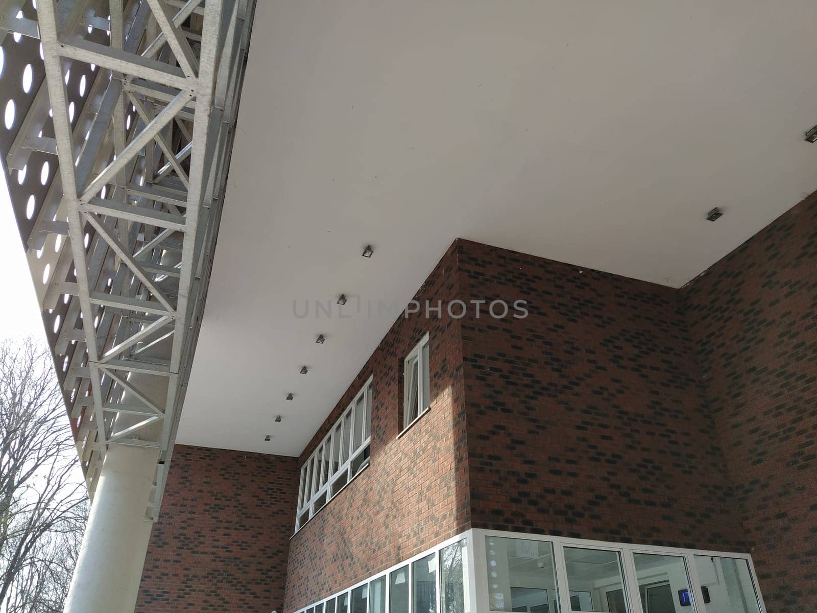 Exterior of the new school. New plastic white windows. Fashionable brown - red facing brick. Metal arch with canopy. Ceiling lighting. School entrance. Serbia, Sremska Mitrovica