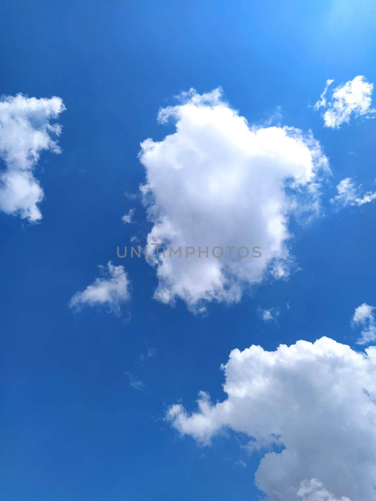 Blue sky and white clouds in sunlight. Beautiful inviting clouds. Summer holidays, travel and vacation.