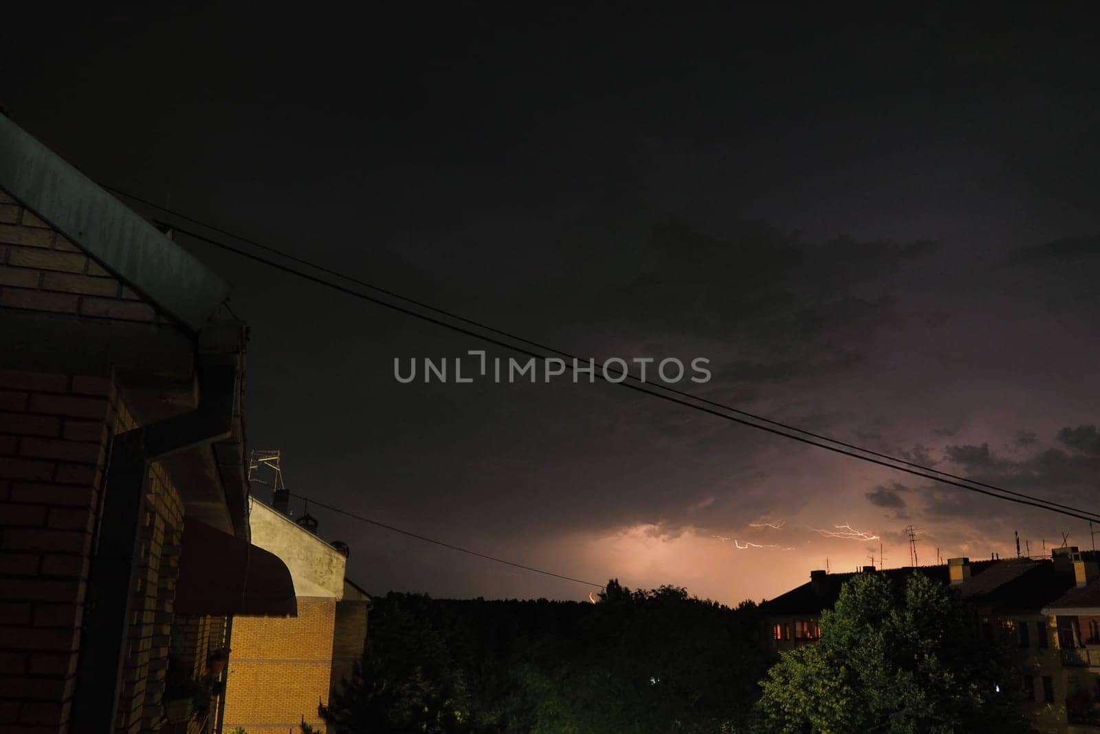 Thunderstorm at night over the city. Flashes of lightning and low clouds. Thunder and lightning. Natural element, climate change and weather forecast concept. Discharge of electricity in the sky