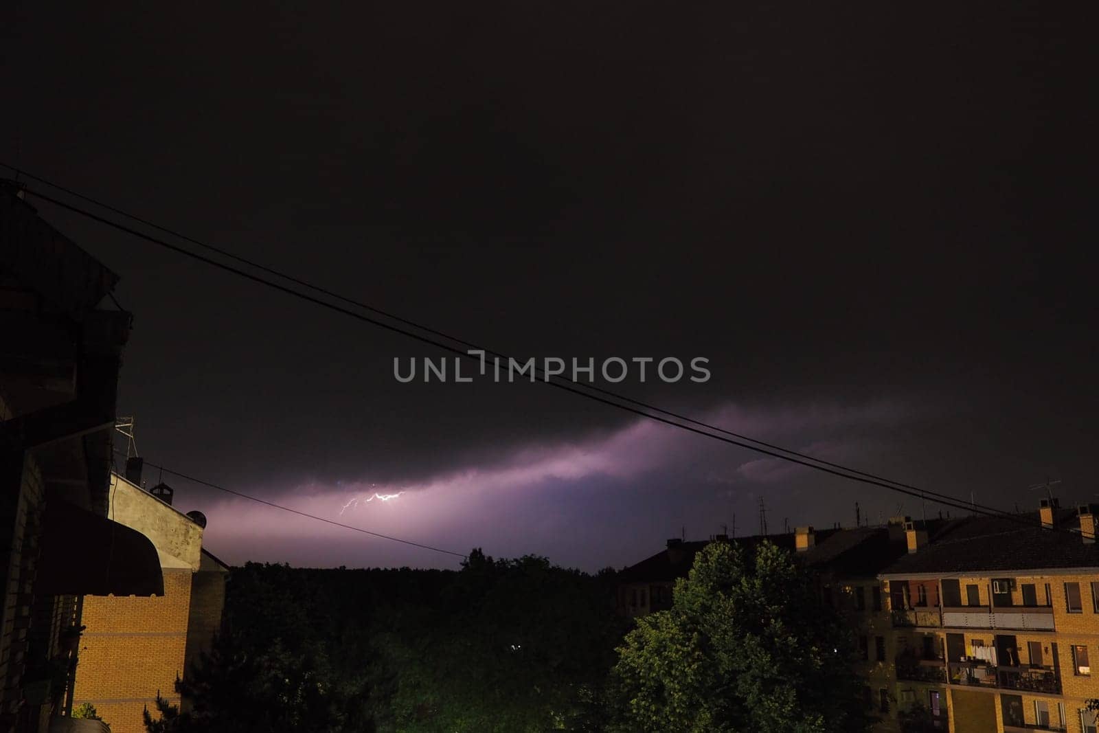 Thunderstorm at night over the city. Flashes of lightning and low clouds. Thunder and lightning. Natural element, climate change and weather forecast concept. Discharge of electricity in the sky